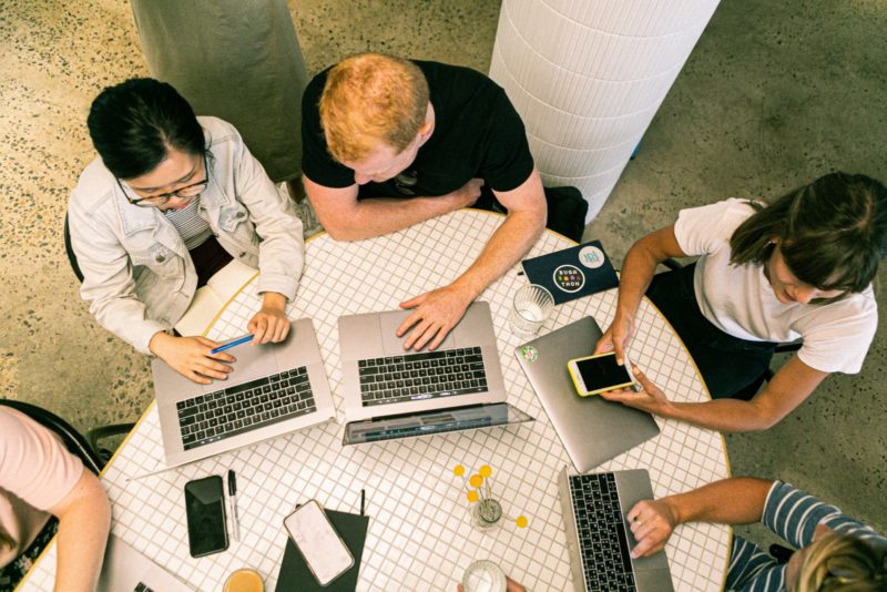 People at a table on laptops and phones